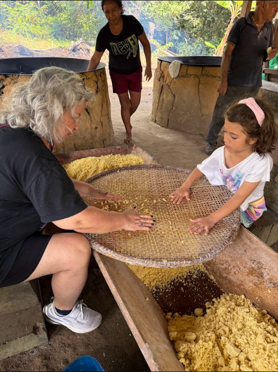 Criança e família participando de vivência comunitária junto à comunidade local.