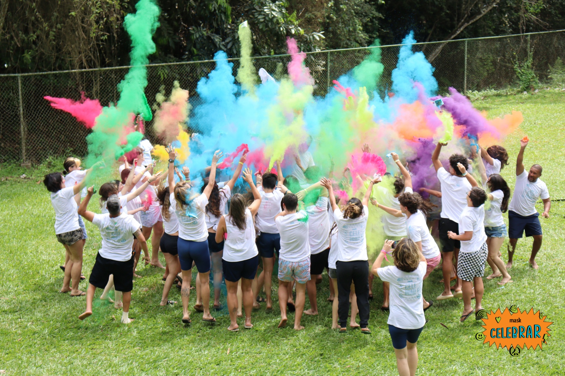 Estudantes celebrando com fumaça colorida em festa de encerramento