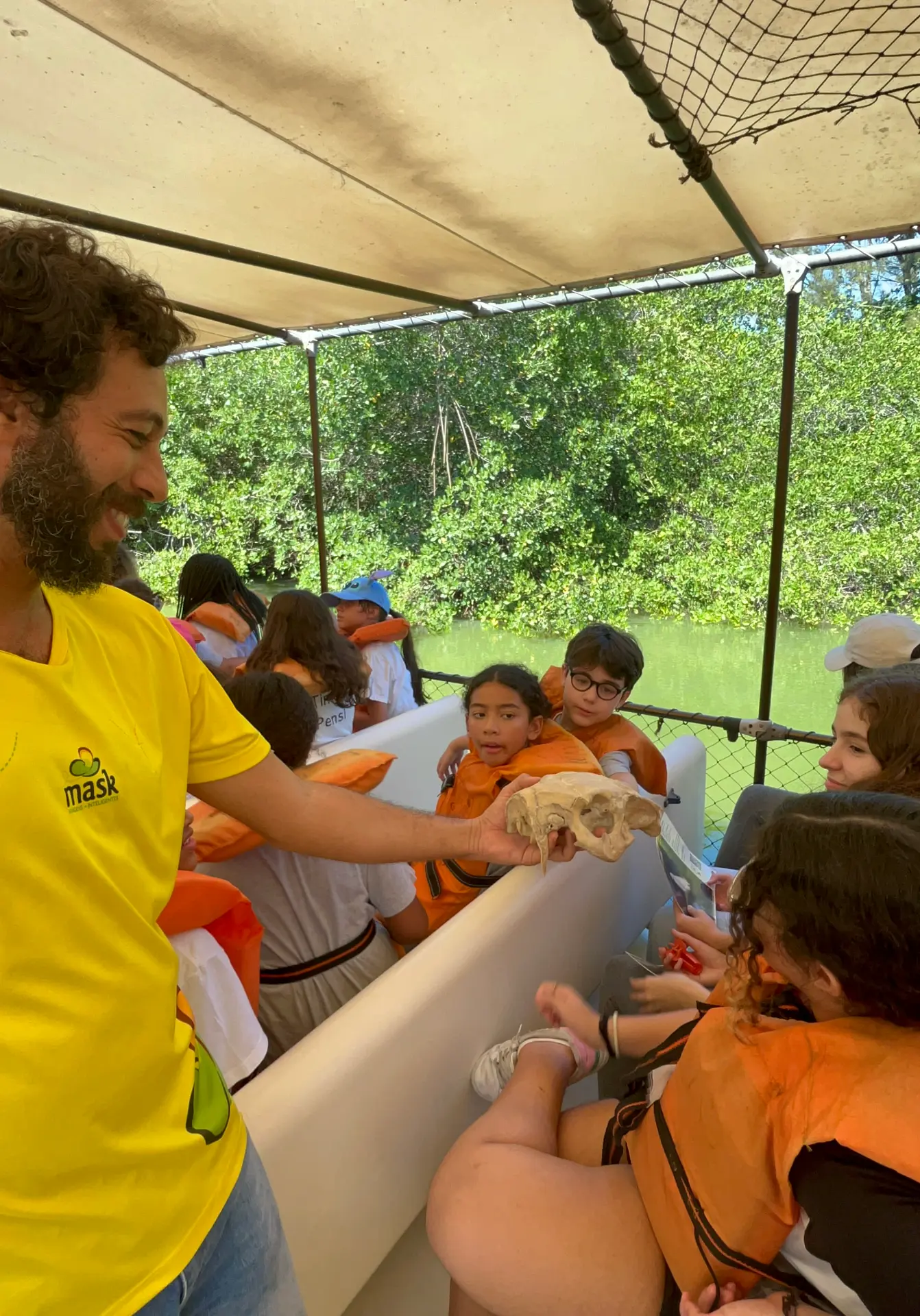 Educador MASK apresentando um crânio de animal para crianças durante uma saída de campo.